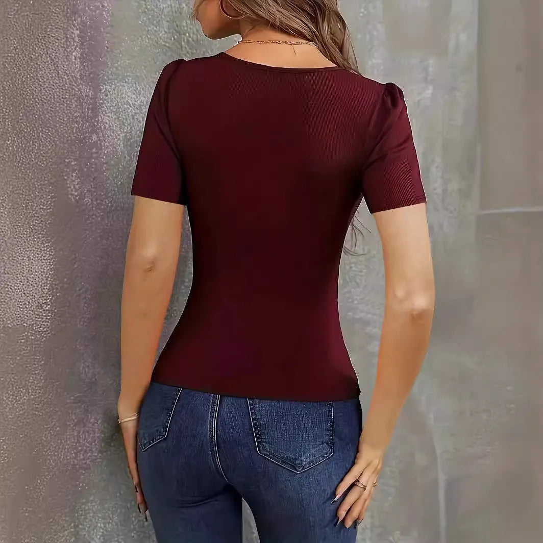 Woman wearing a wine red knitted short sleeve top with a low neckline and slim fit.