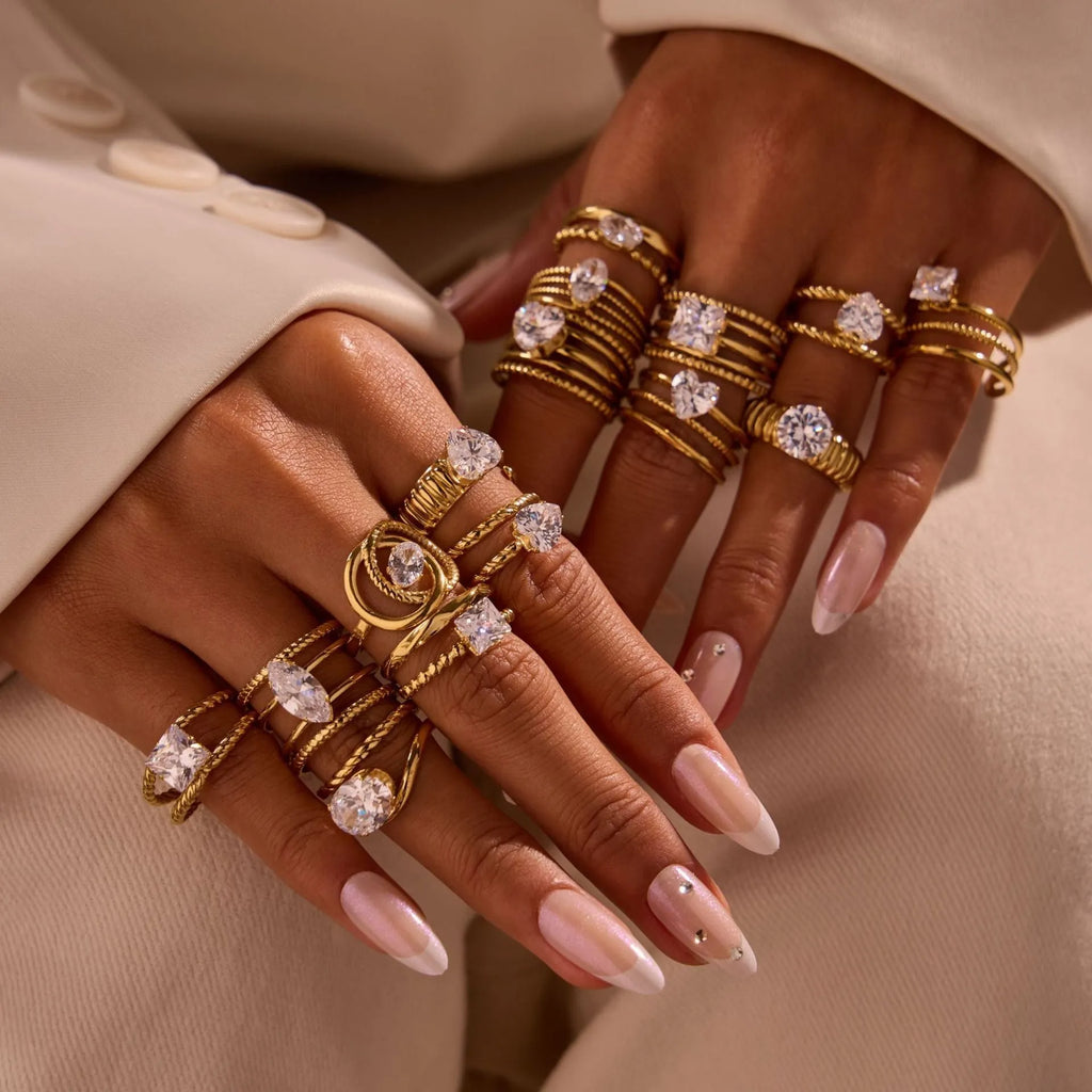 Gold-coloured stainless steel ring with an inlaid zircon stone and geometric heart design on an adjustable open mouth band.