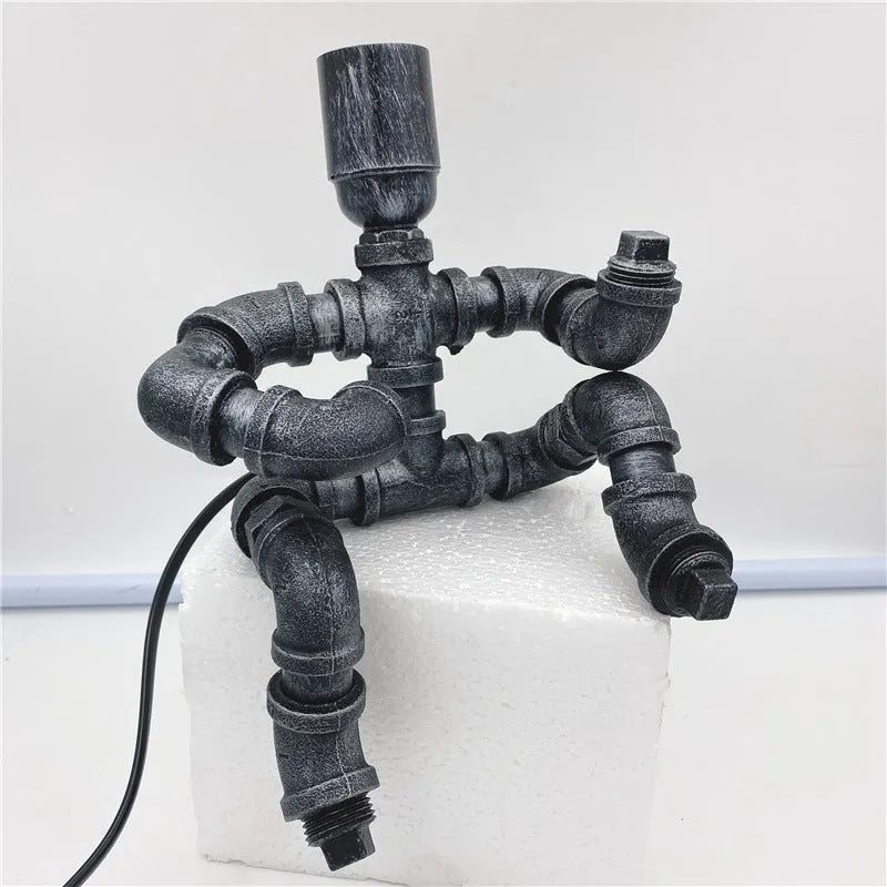Industrial retro style table lamp made from iron pipes with a robot figure detail, in a vintage finish.