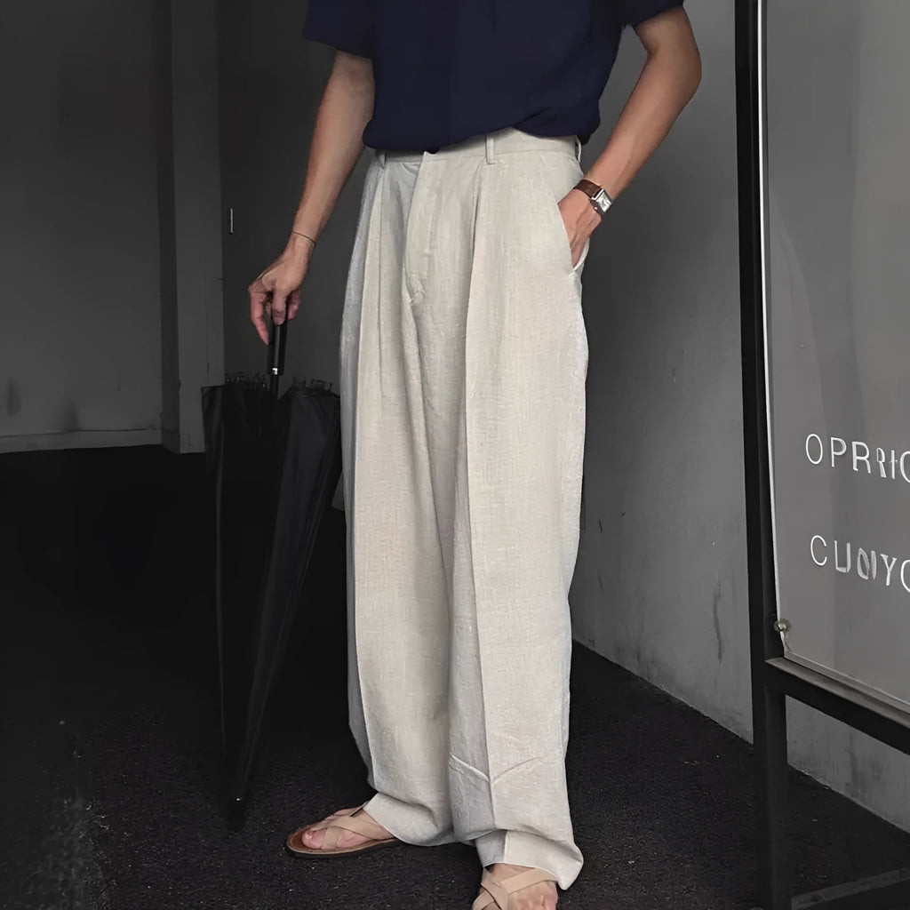 Men's apricot coloured loose-fit cotton linen trousers with a pencil leg and elastic waist on a neutral background.