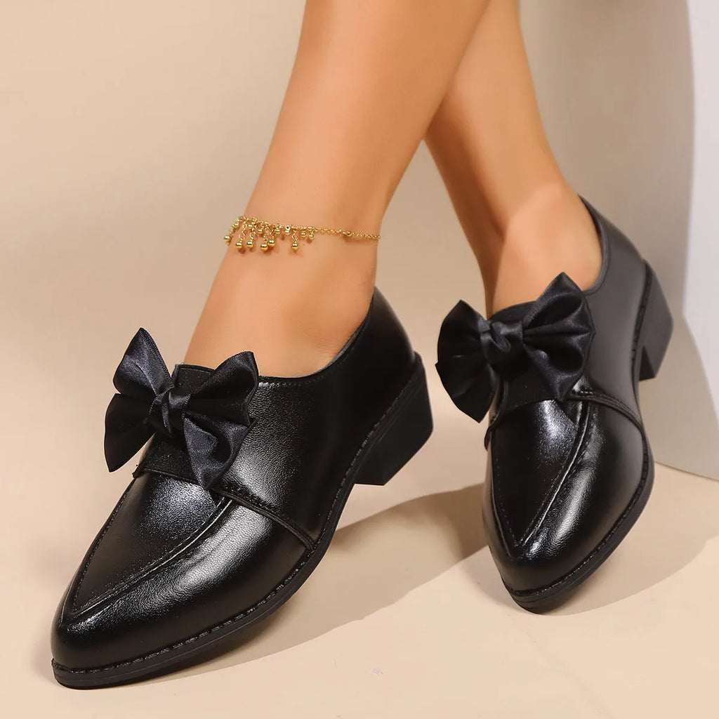 Women's brown PU leather slip-on shoe with a large bow on the pointed toe.