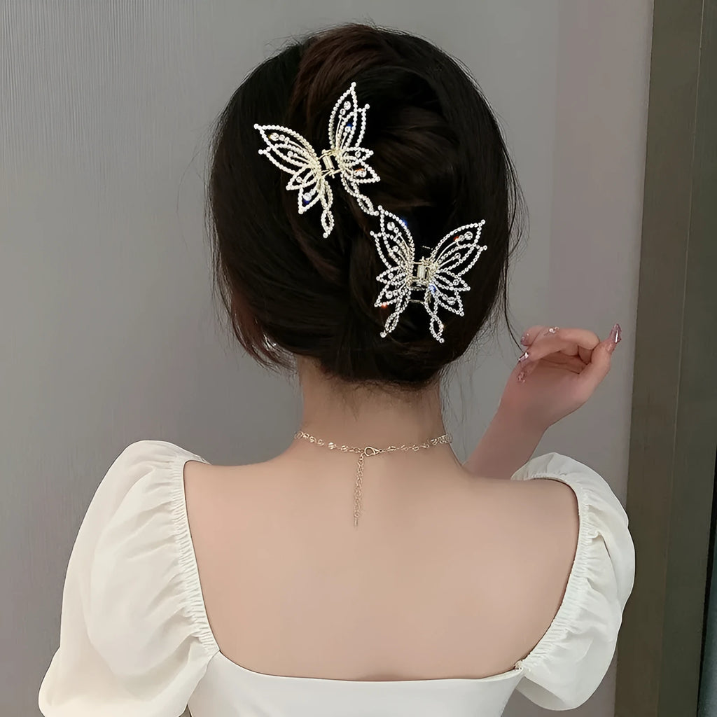Butterfly-shaped alloy hair clip with electroplated finish in pearl or rhinestone style.