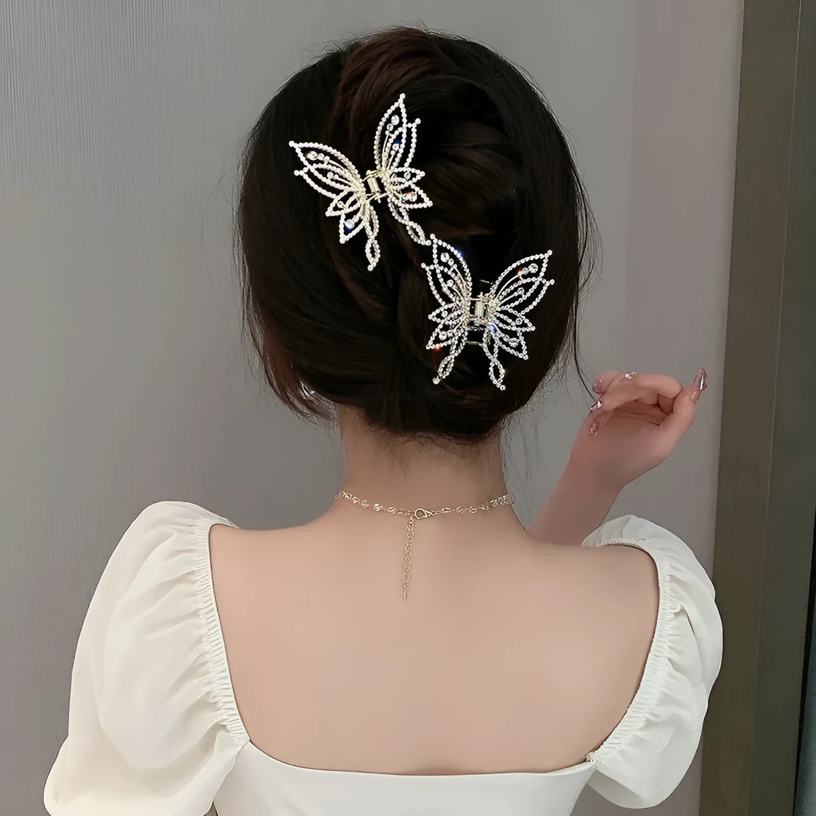 Butterfly-shaped alloy hair clip with electroplated finish in pearl or rhinestone style.