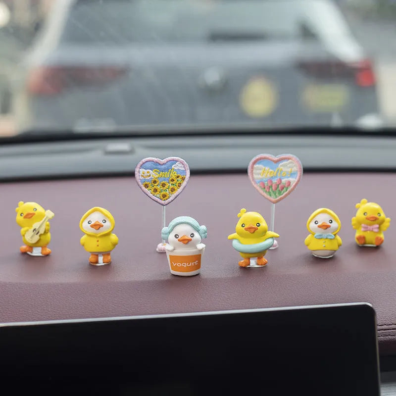 Yellow PVC cartoon duckling car decoration set with six ducks and a Hello sign on a car dashboard.