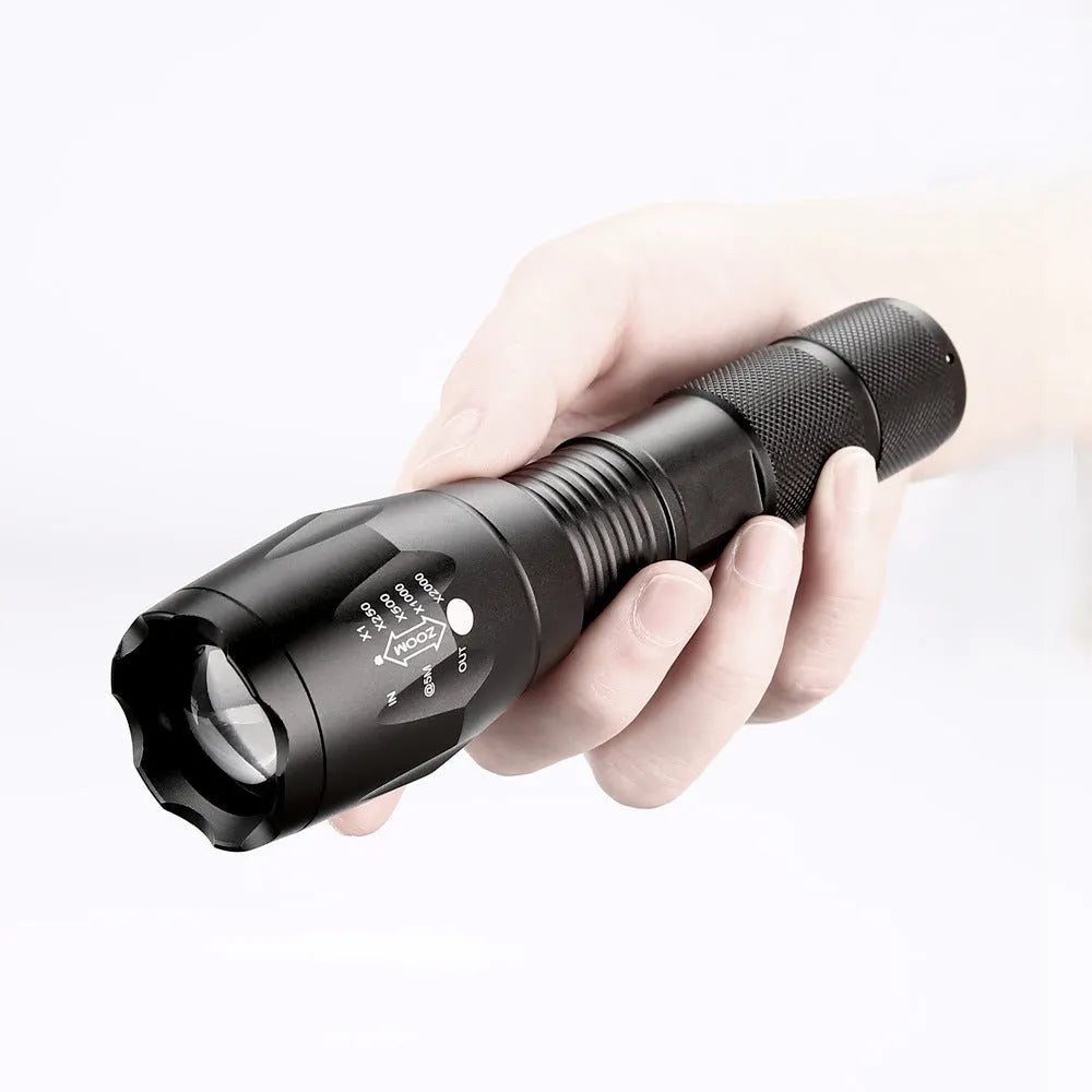 Black aluminium alloy LED zoom flashlight with adjustable focus head on a dark background.