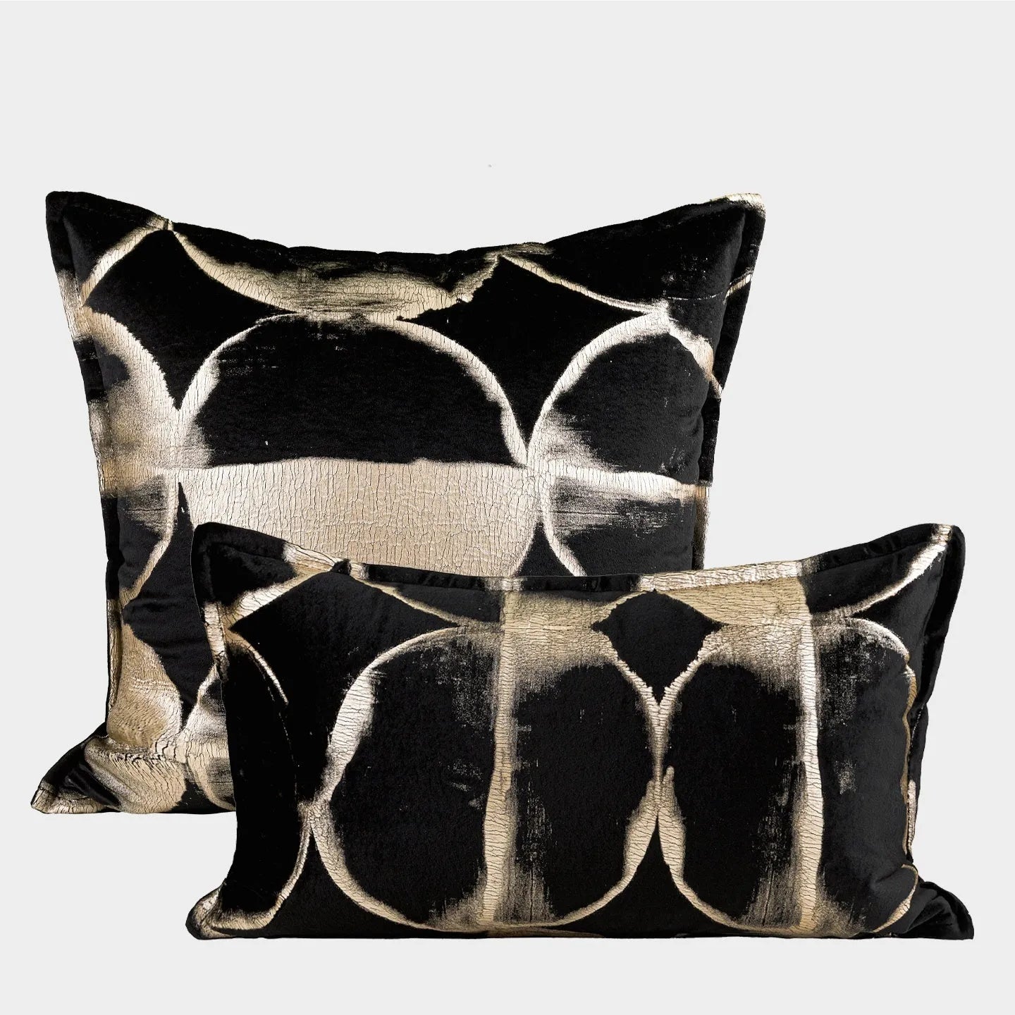 Black and gold abstract patterned flannel decorative cushion on a grey sofa.