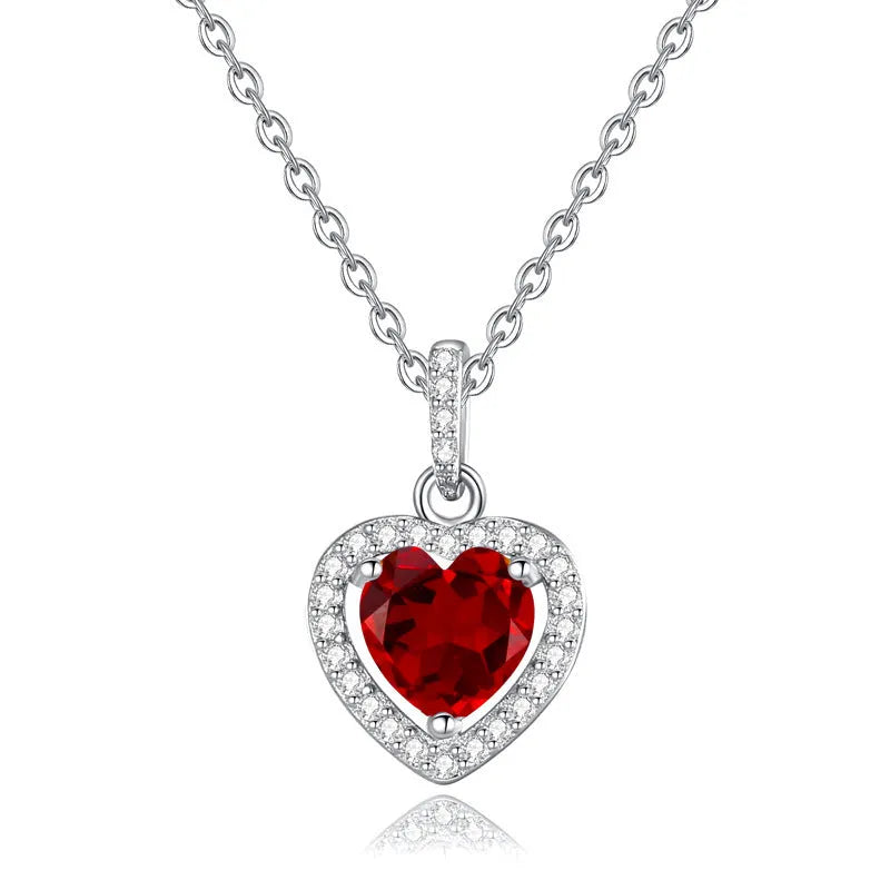 Close-up of a sterling silver heart pendant necklace with an inlaid amethyst gemstone on a cross chain.