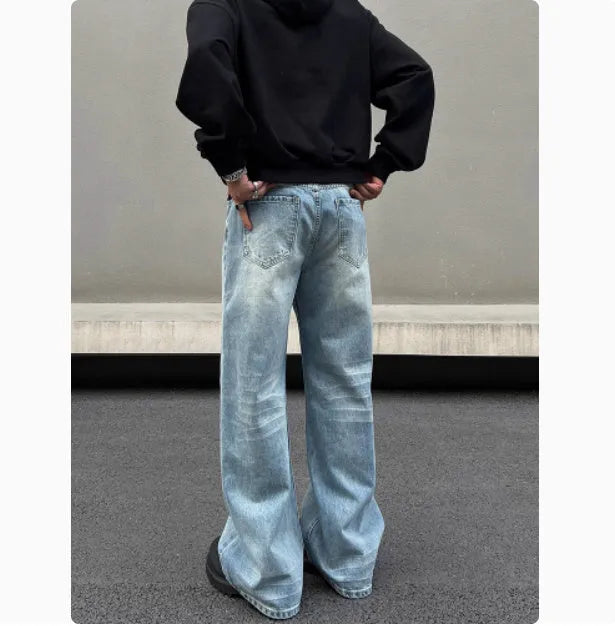 Men's blue straight-leg denim jeans with a whisker wash effect, showing a flared leg and visible stitching detail.