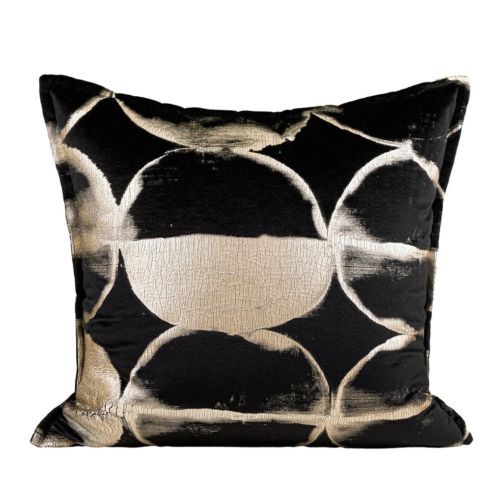 Black and gold abstract patterned flannel decorative cushion on a grey sofa.