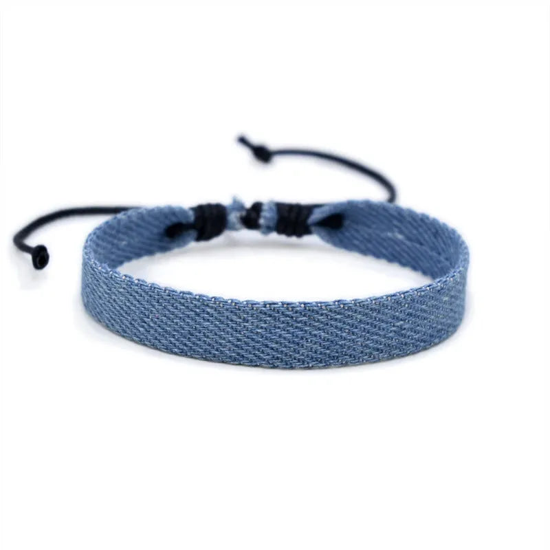 Denim fabric bracelet carrying strap showing mixed material construction and traditional closure mechanism