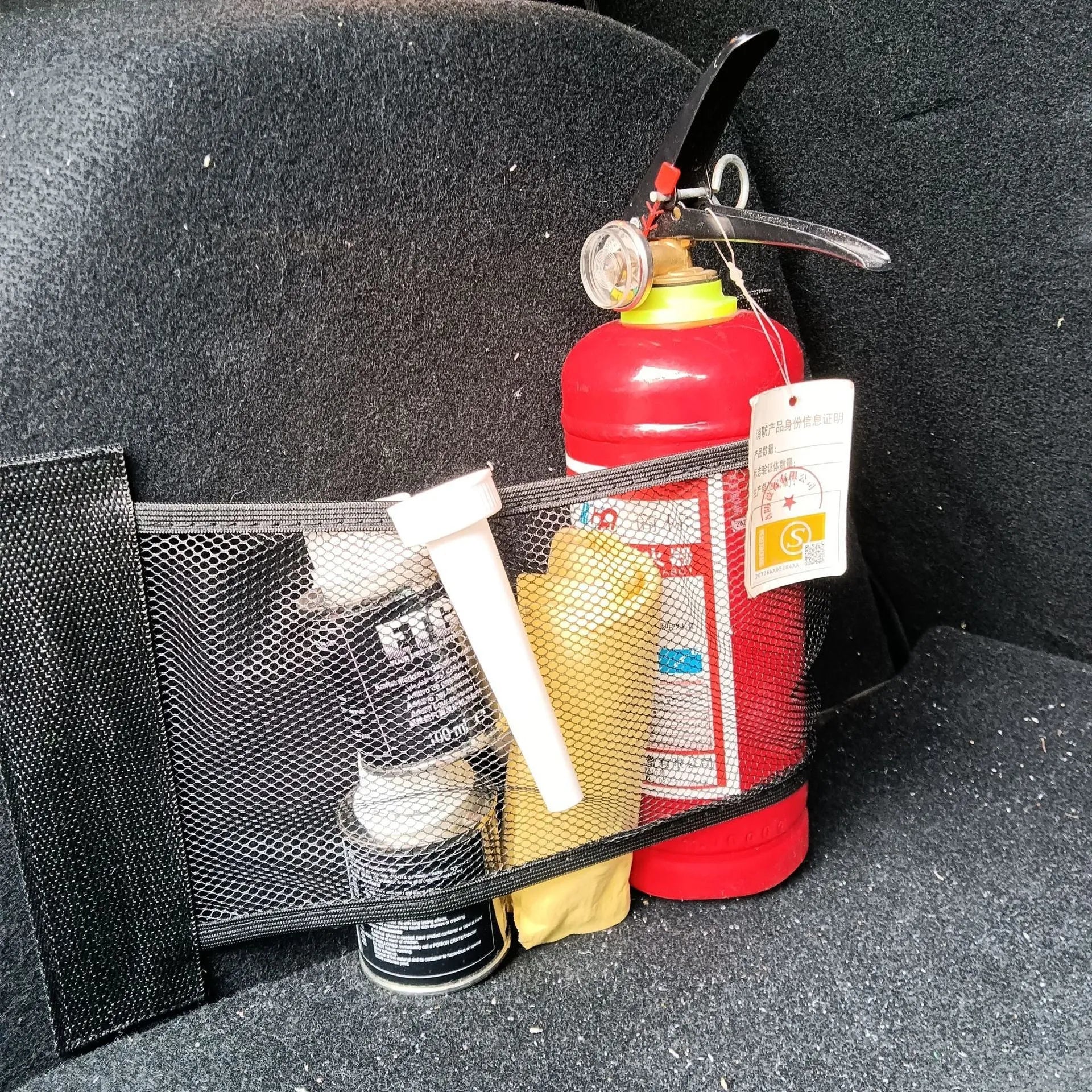 Elastic polyester car boot storage net shown with metal hooks and adhesive strips for organising loose items.