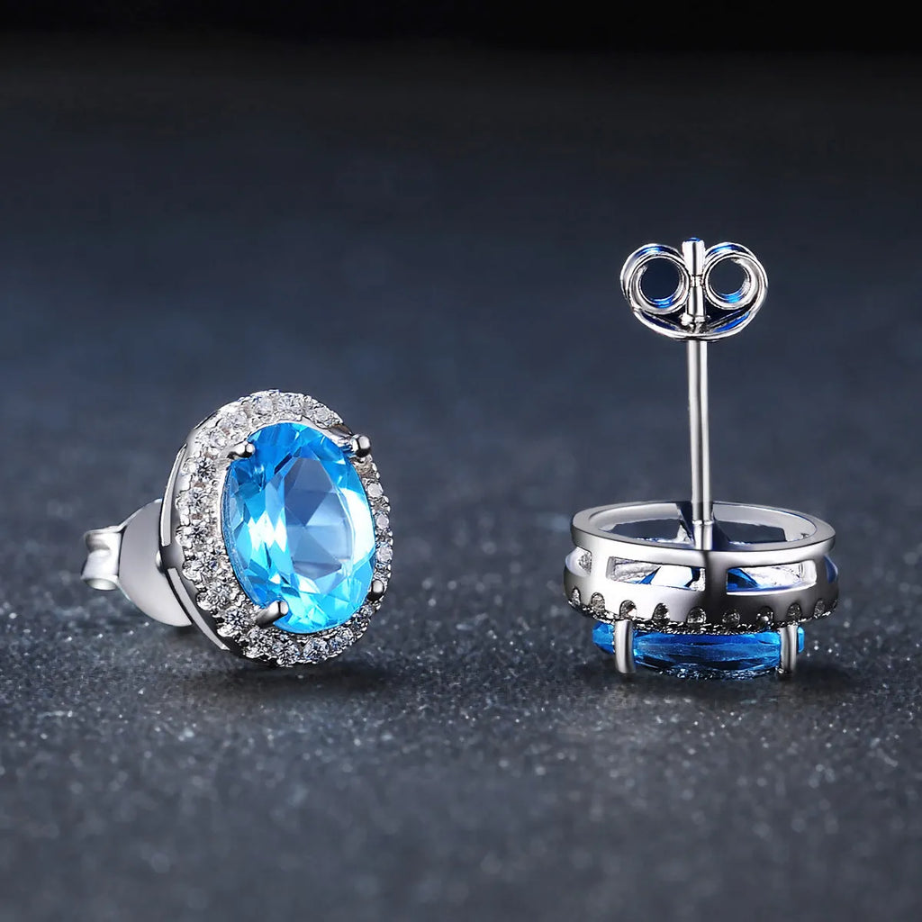 Four-piece sterling silver jewellery set with blue topaz stones: geometric earrings, ring, pendant, and necklace.