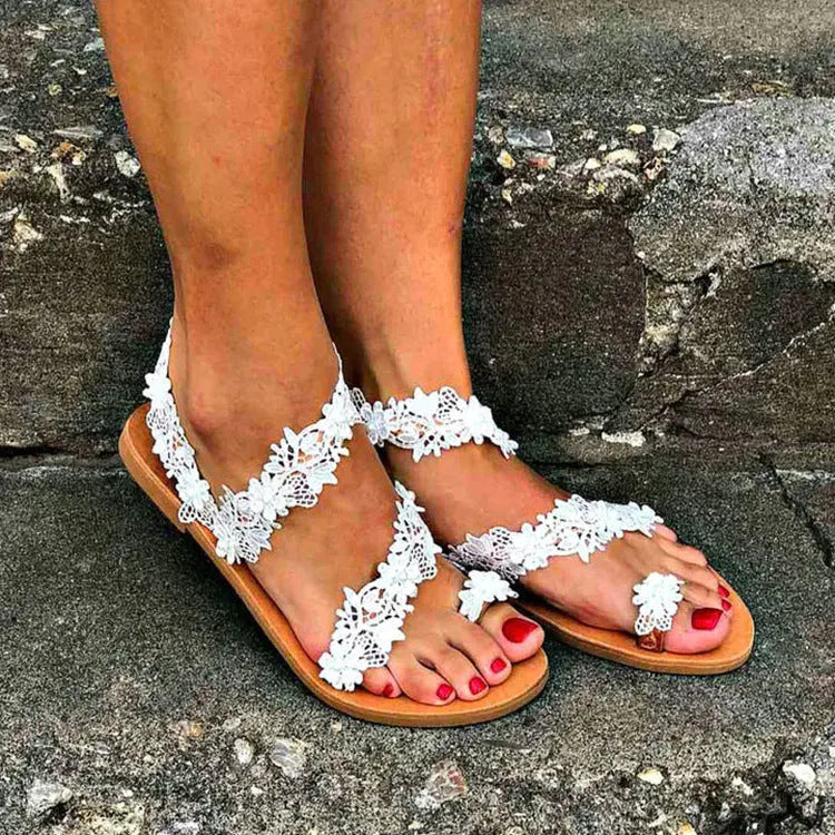 White women's flat sandals with rhinestone flower decoration on the upper.