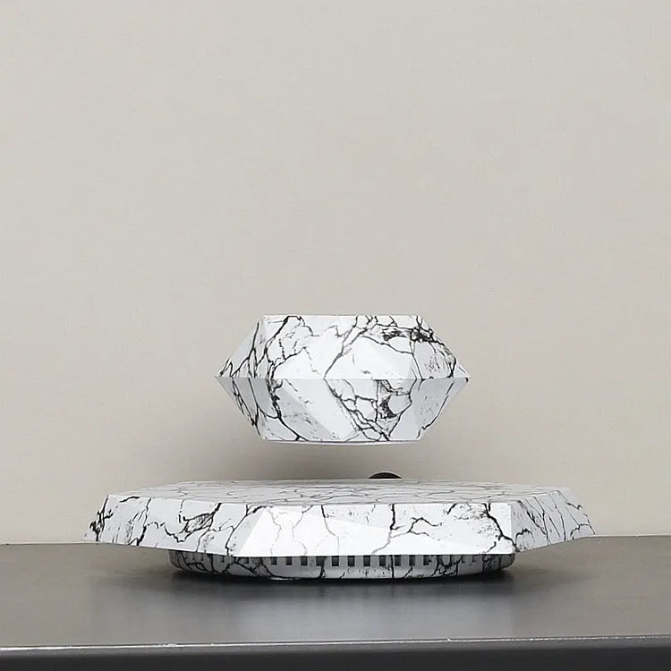 Marble-coloured levitating plant pot floating above magnetic base with small indoor plant