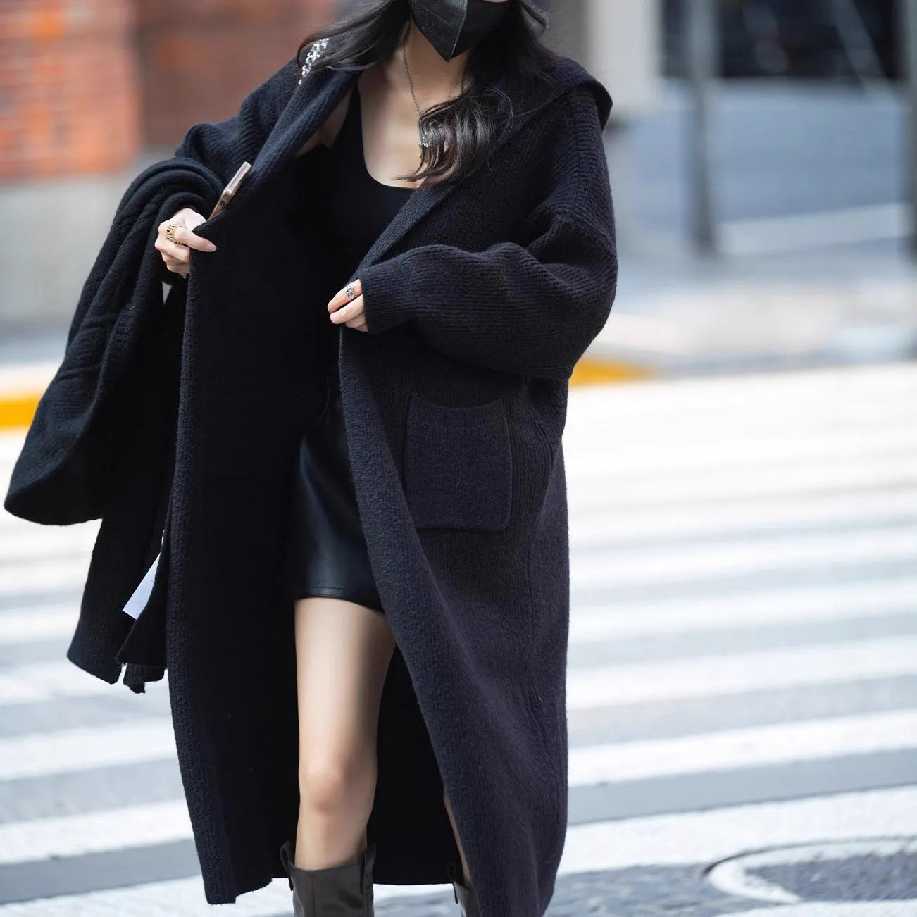 Long grey knitted women's cardigan with hood, modelled as a loose-fit trench coat.