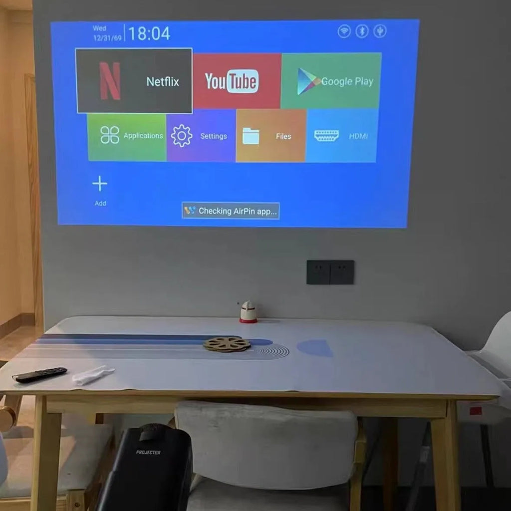 White home projector with carrying handle on a table, set up for wireless gaming projection.