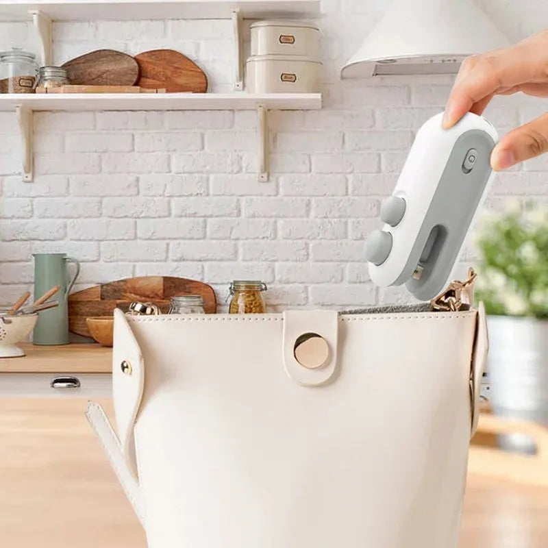 Handheld vacuum bag sealer in blue with USB charging port and cutter blade