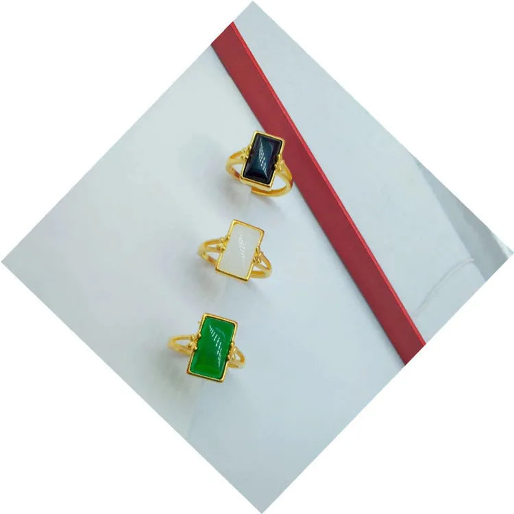Gold-plated adjustable brass ring with a central inlaid gemstone, shown in black, green, and white colour options.