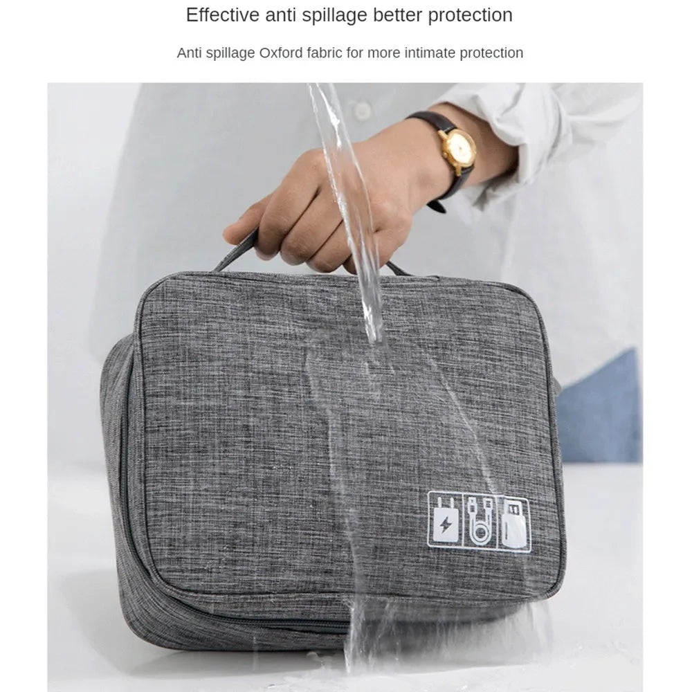Black travel cable organiser bag open, showing mesh pockets, elastic loops, and removable padded dividers.