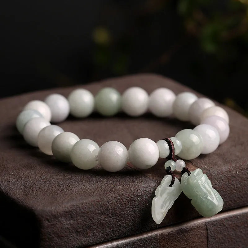 Natural green jade bracelet with a hanging Maitreya Buddha charm on a wrist.