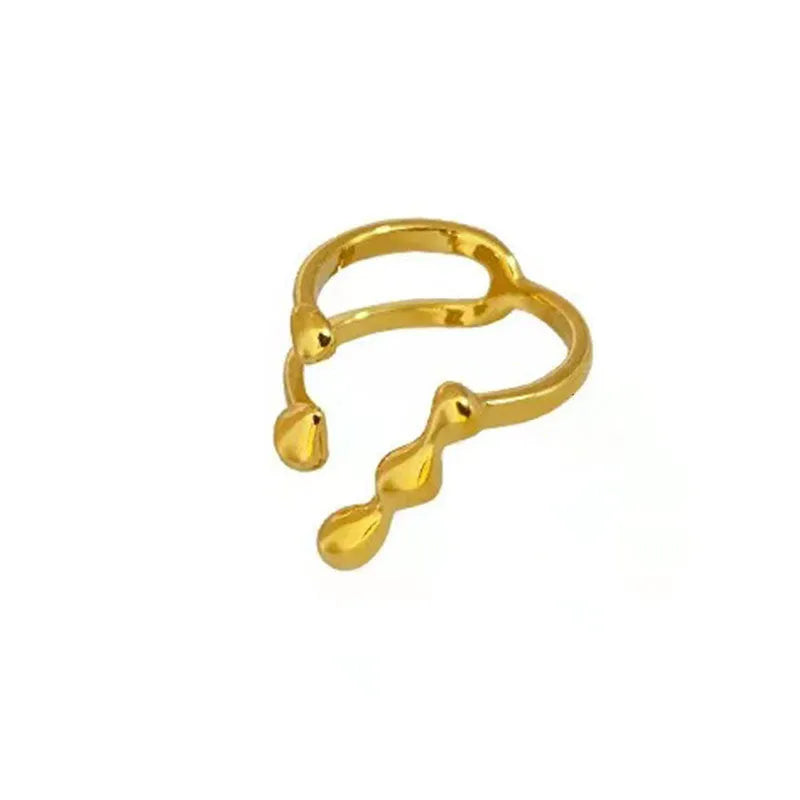 Gold and silver coloured brass opening ring with spherical design on a white background.