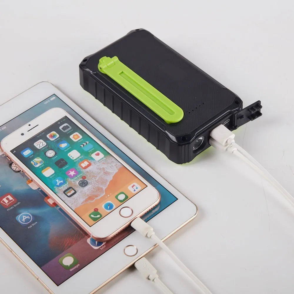 Orange and green hand crank solar power bank with 12000mAh capacity showing USB ports and LED torch