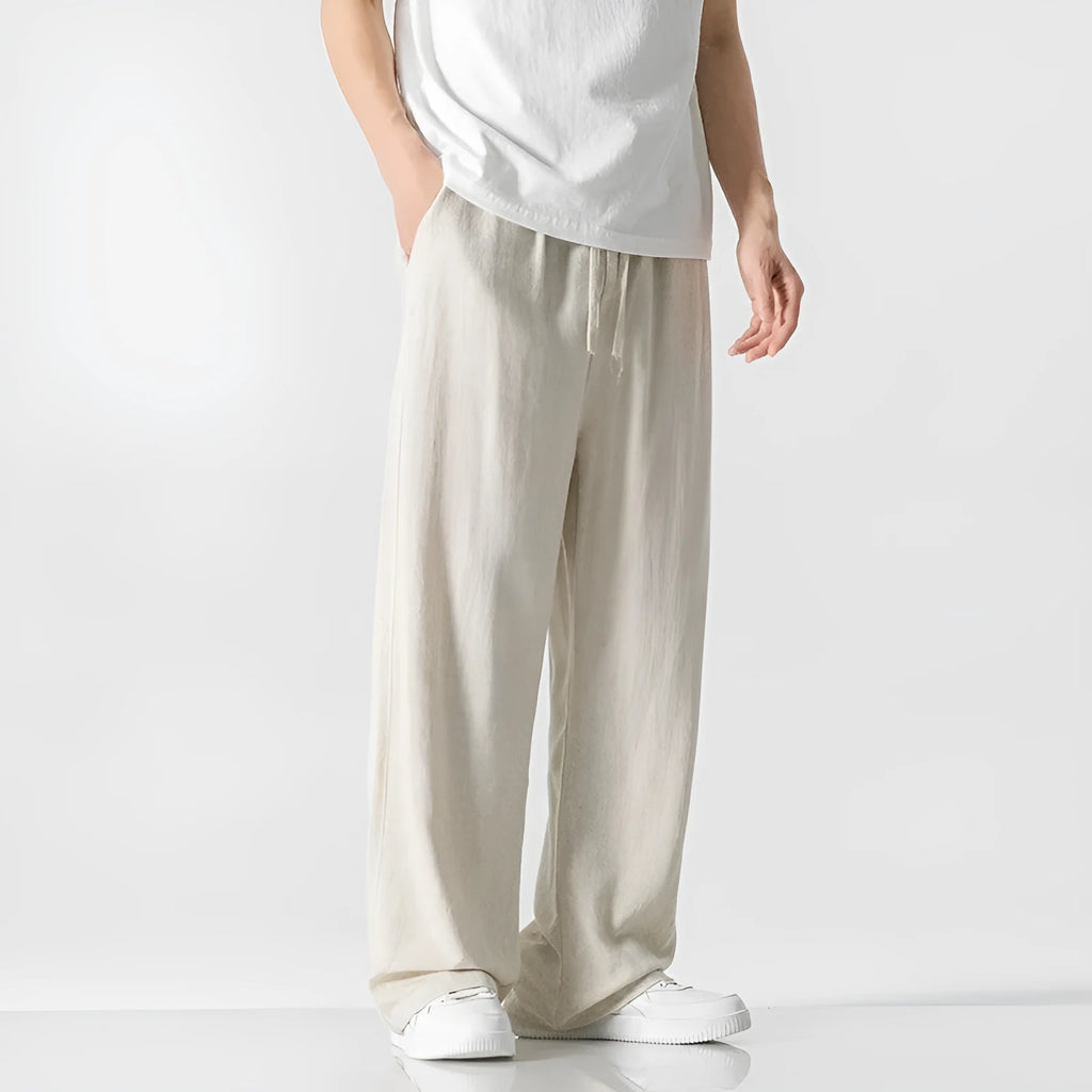 Men's beige loose-fit linen-style bamboo fibre trousers with a cropped leg and drawstring waist laid flat.
