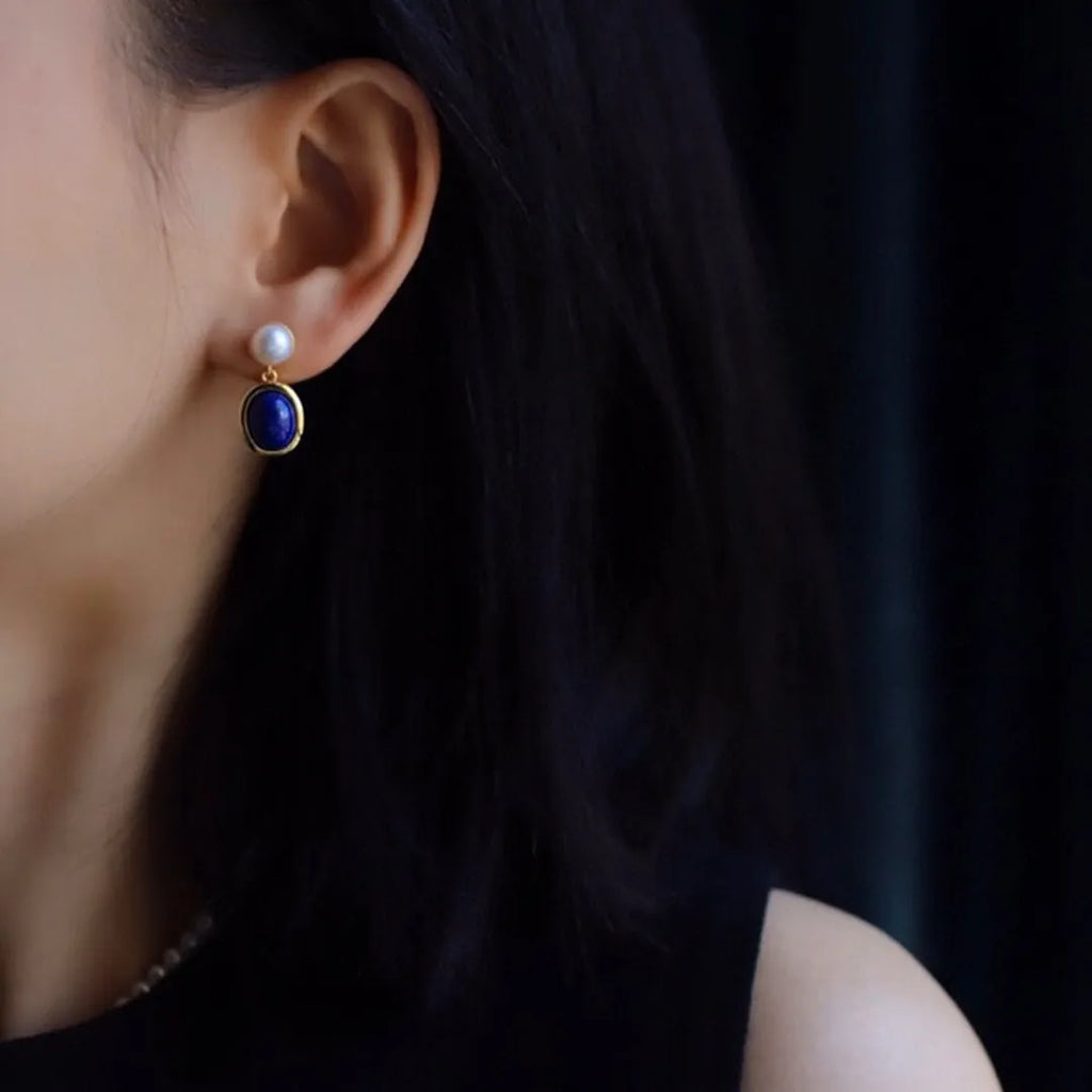 A pair of simple sterling silver earrings featuring a blue lapis lazuli pearl and auspicious patterns.