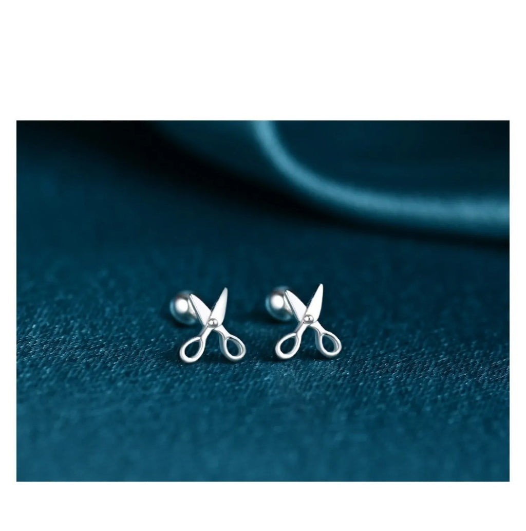 A pair of pure silver screw-style ear nails featuring a miniature scissors charm.