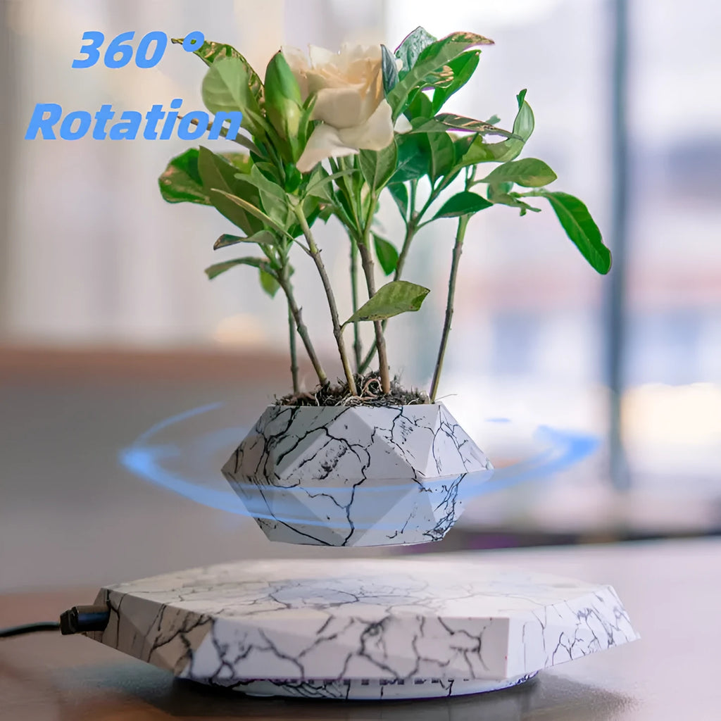 Marble-coloured levitating plant pot floating above magnetic base with small indoor plant