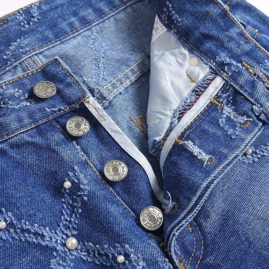 Pearl embroidery street trendy denim skinny pants in blue with mid-rise tapered leg and embroidered pearl details.