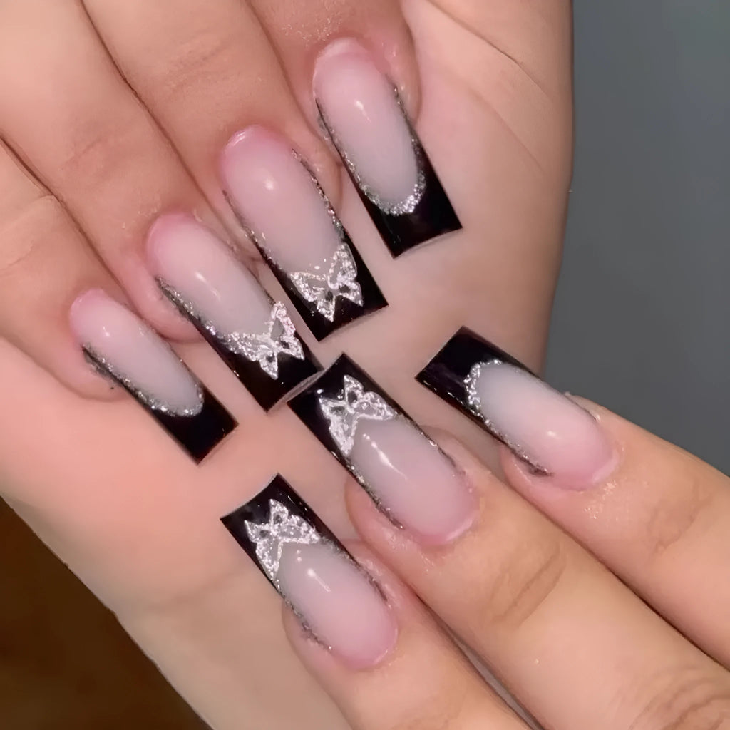 Black French style false nails with glittering butterfly decoration on medium length press-on nails.
