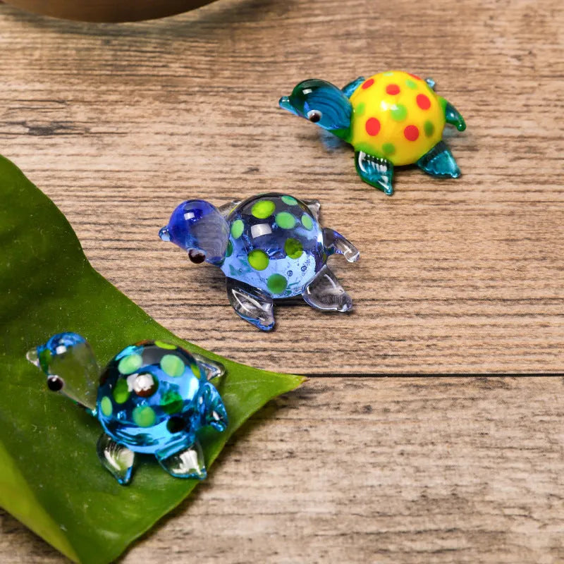 Set of six geometric glass turtle ornaments in various colour combinations on a desktop.