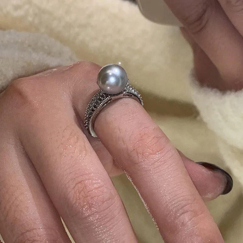 Copper geometric open ring with a black pearl, shown on a woman's index finger.