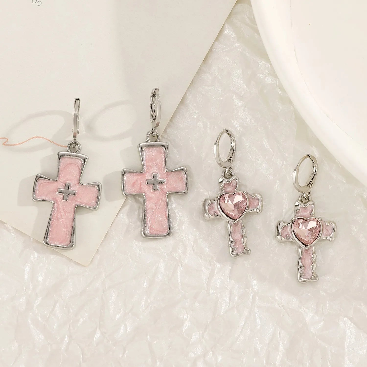 Women's alloy earrings with cross and heart designs in white, black, and silver colour options.