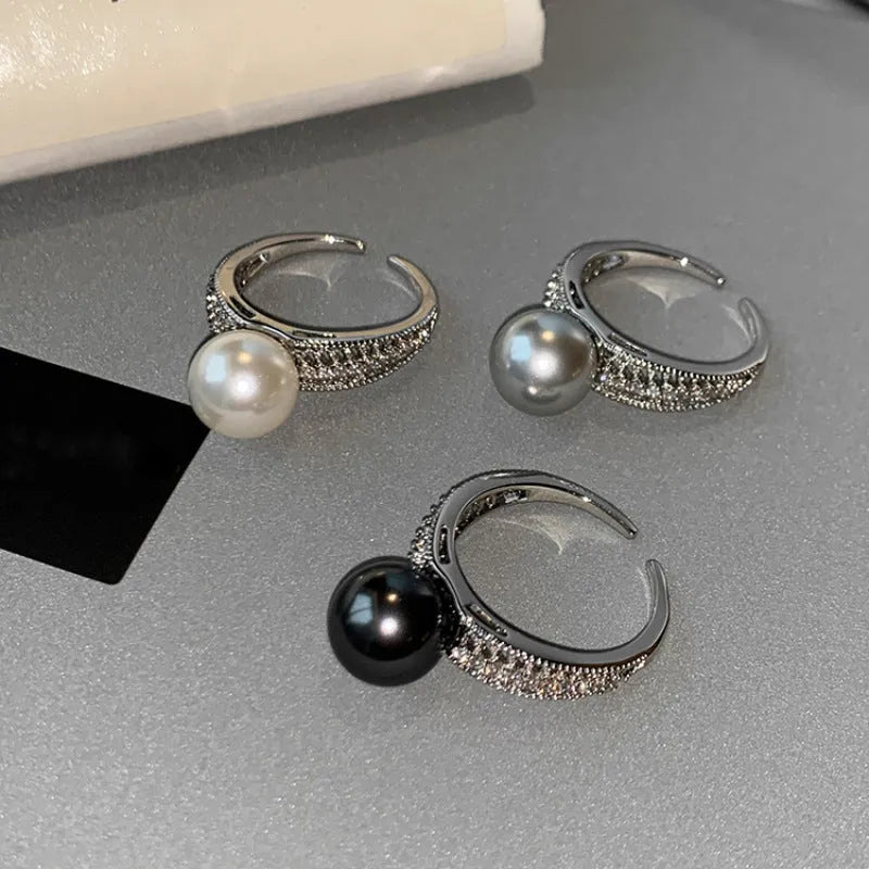 Copper geometric open ring with a black pearl, shown on a woman's index finger.