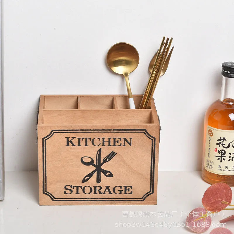 Open-top wooden kitchen storage box with internal grid divider for organising utensils.