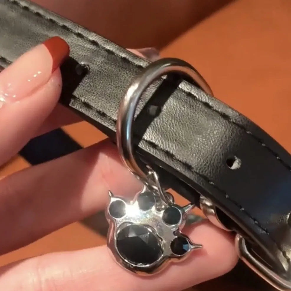 Black bell-shaped choker neck collar showing cat paw, bone, and leather style designs on an adjustable band.