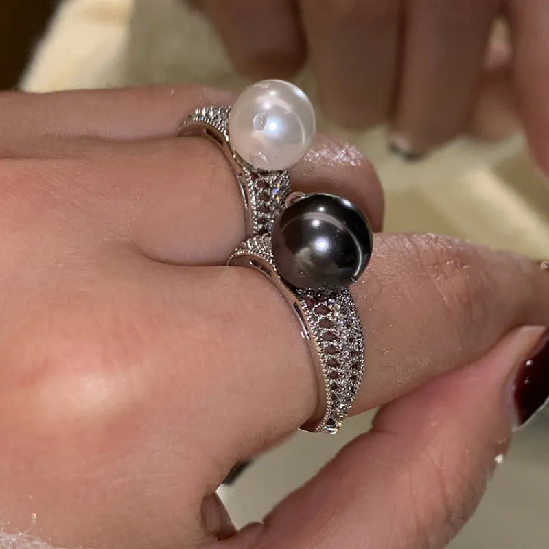 Copper geometric open ring with a black pearl, shown on a woman's index finger.
