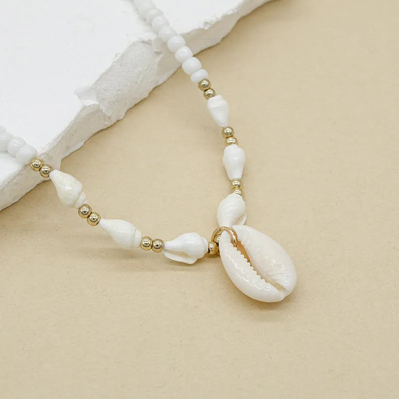 White shell bead necklace with conch pendant and mother-of-pearl detail