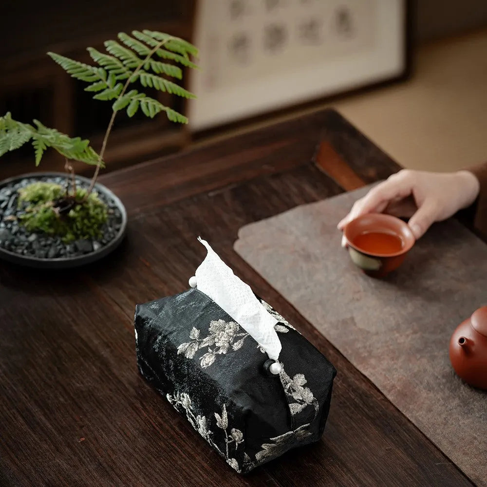 Chinese brocade fabric tissue box cover with embroidered white plum pattern, shown with and without a pearl buckle clasp