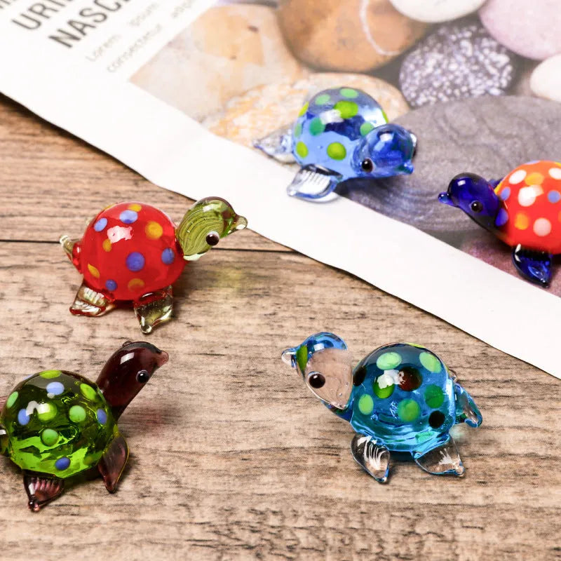 Set of six geometric glass turtle ornaments in various colour combinations on a desktop.
