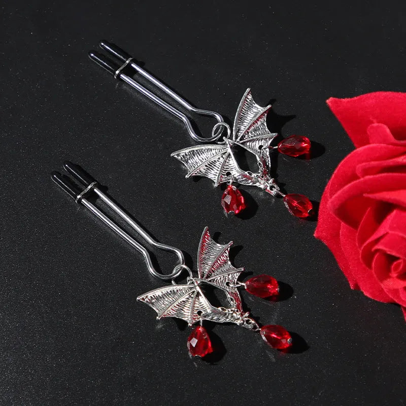 Silver alloy bat-shaped nipple clamp with ruby details and adjustable rubber-padded mechanism.