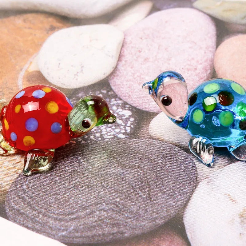 Set of six geometric glass turtle ornaments in various colour combinations on a desktop.