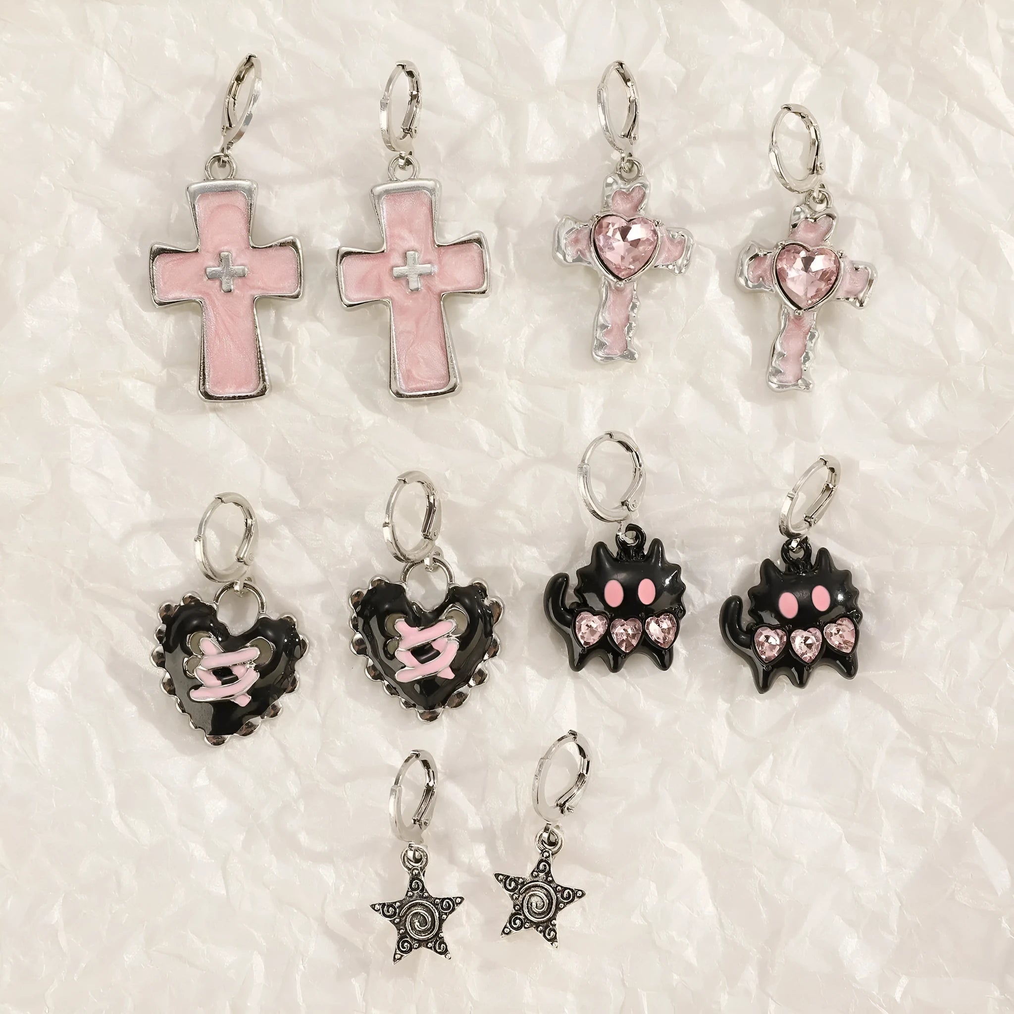 Women's alloy earrings with cross and heart designs in white, black, and silver colour options.