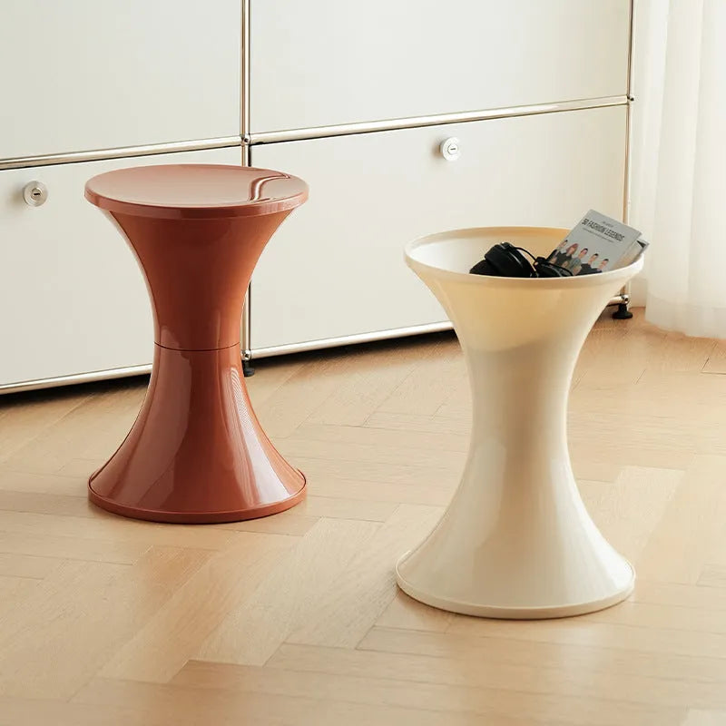 A green plastic hourglass-shaped shoe changing stool on a wooden floor.
