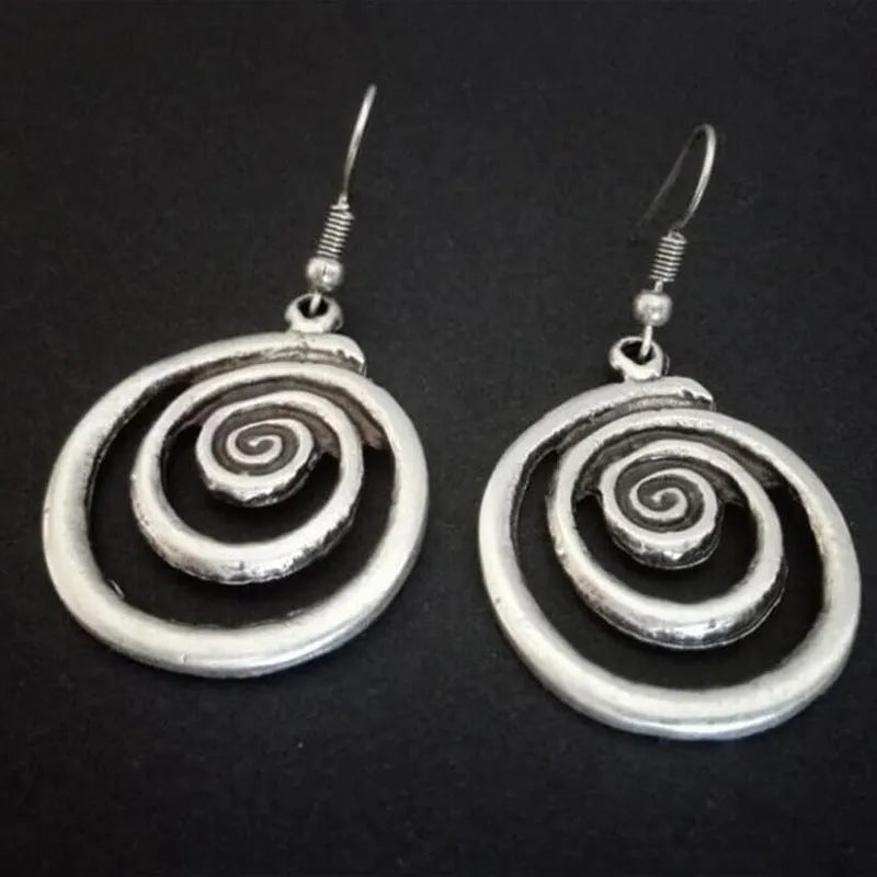 Close-up of a pair of silver geometric spiral earrings with a distressed vintage finish.