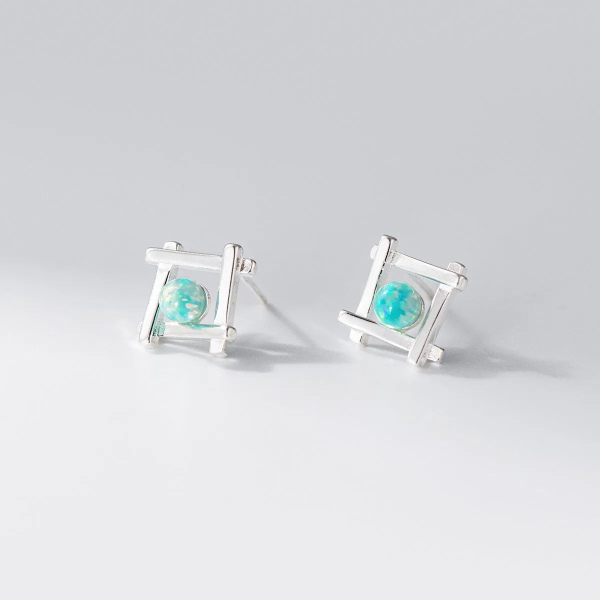 Geometric cross-shaped quadrangle stud earrings in sterling silver, shown in both silver and gold-plated finishes.