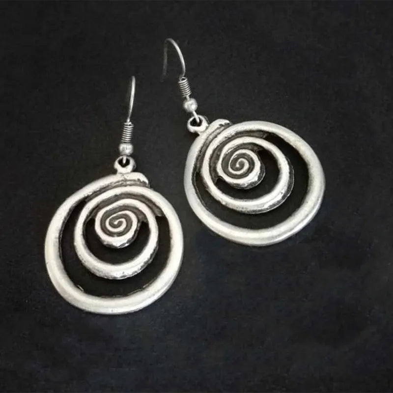 Close-up of a pair of silver geometric spiral earrings with a distressed vintage finish.