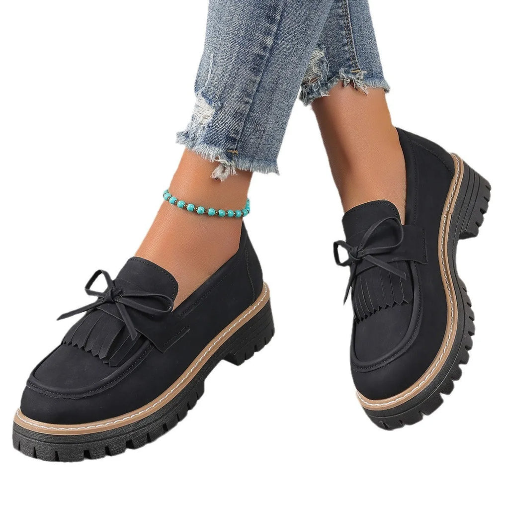 Black women's loafers with a tassel and bowknot decoration on the front.
